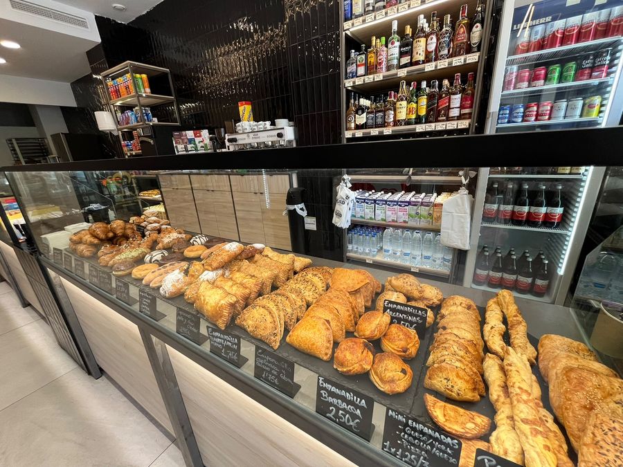 Vitrina de una tienda LSD con empanadillas y hojaldres salados, con neveras de bebidas al fondo